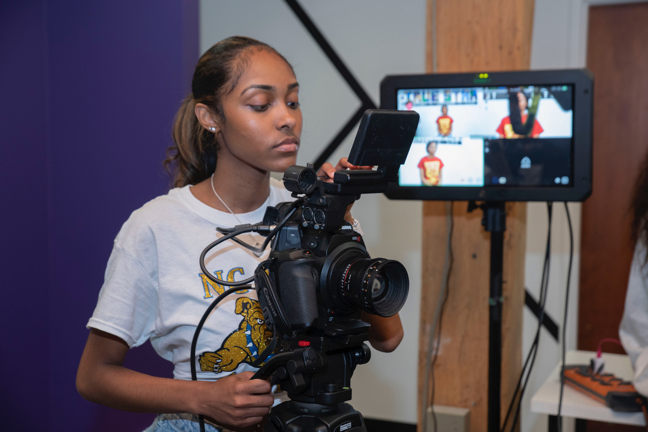A young person focused on a camera in a studio