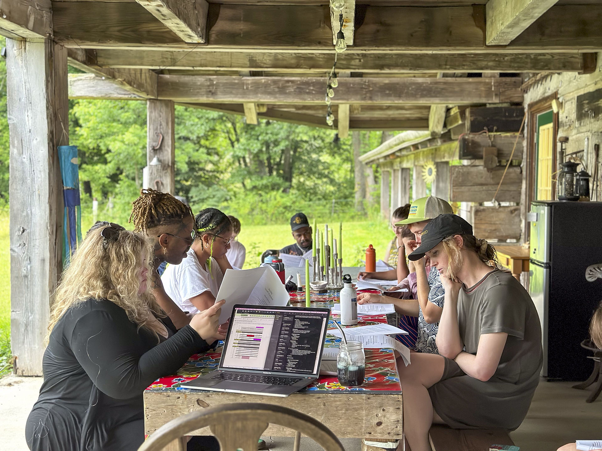 a group of artists outside at a table reviewing documents