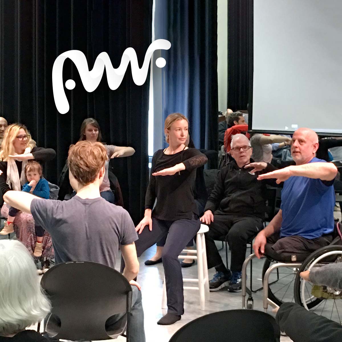 A group of people taking movement instructions with a dancer in a wheelchair